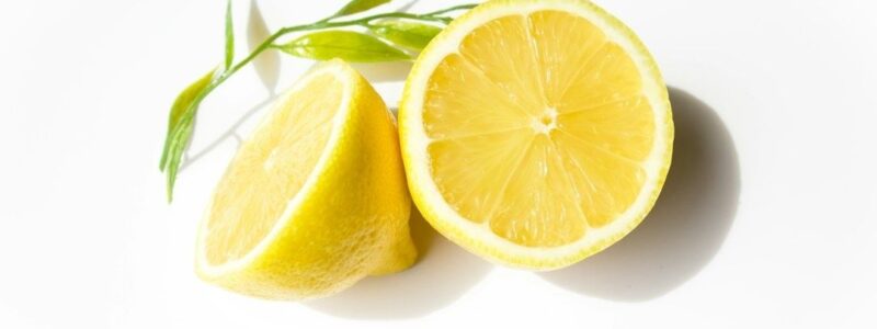 Två halverade citroner med gröna blad på vit bakgrund