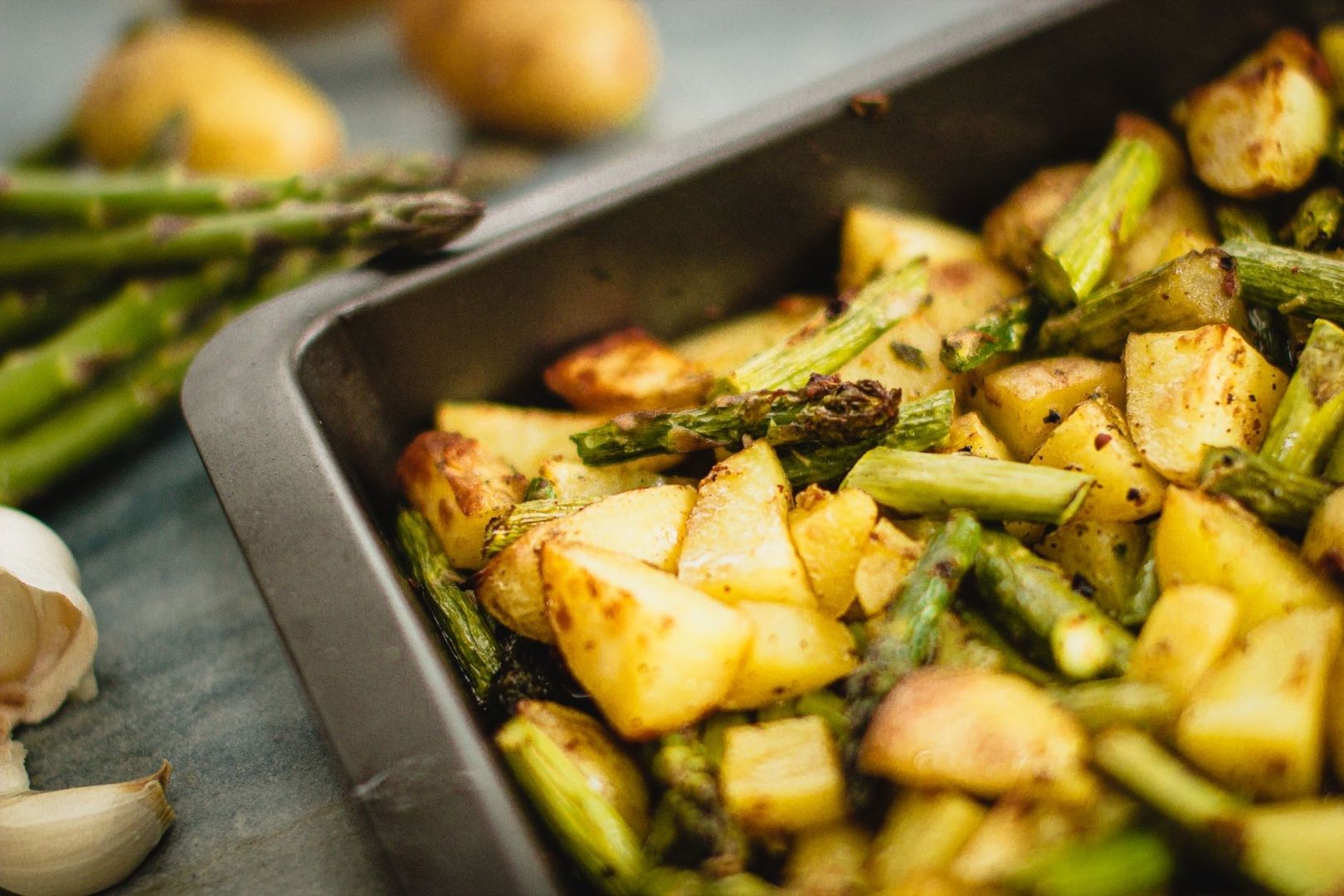 Ugnsrostad potatis och sparris på en plåt
